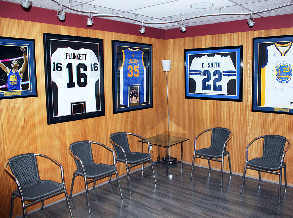 Five empty chairs in the reception area with hanging frames of famous athletes jerseys.