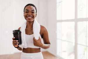 Black girl smiling with braces holding a towel around her neck and a sports drink cup.