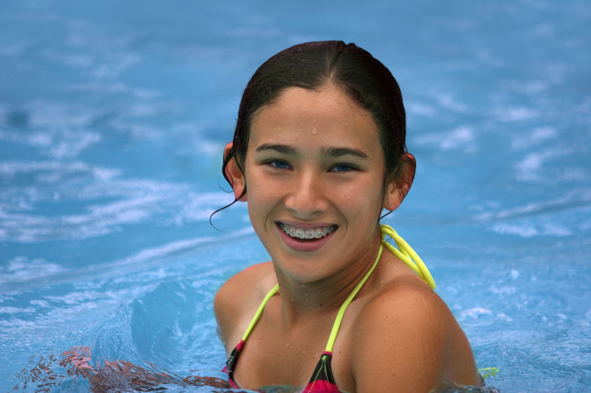 Happy teen girl with braces in the pool